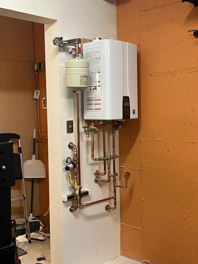 Plumbing technician inspecting water heater connections in Tinicum